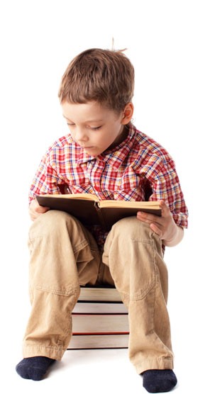 Boy sitting on stack of books reading